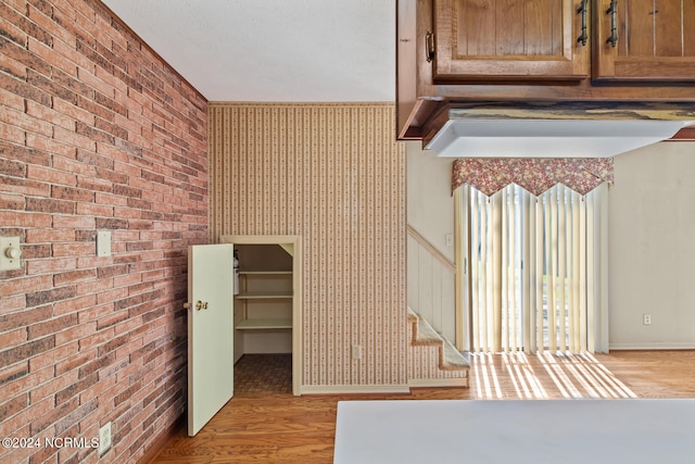 interior space with brick wall and light hardwood / wood-style flooring