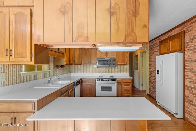 kitchen with white appliances, light hardwood / wood-style floors, brick wall, and sink