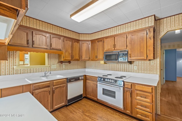 124 N Lisk Dr, Swansboro, NC 28584 - kitchen with a sink, white appliances, light countertops, wallpapered walls, and light wood-type flooring