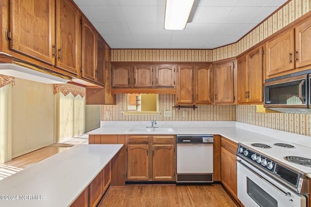 kitchen with white appliances, sink, and light wood-type flooring