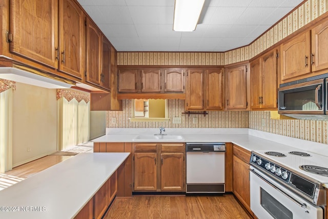 124 N Lisk Dr, Swansboro, NC 28584 - kitchen with brown cabinetry, white appliances, light wood-style floors, light countertops, and a sink