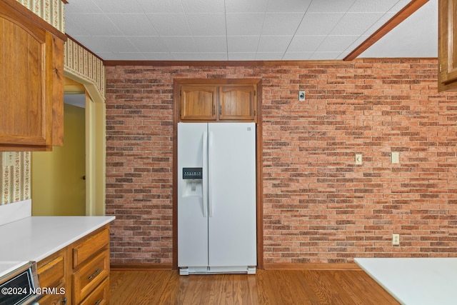 124 N Lisk Dr, Swansboro, NC 28584 - kitchen with brick wall, white refrigerator with ice dispenser, light countertops, brown cabinets, and light wood finished floors