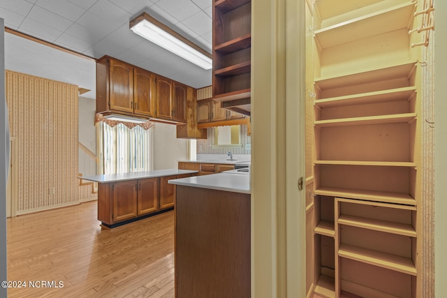 kitchen featuring a breakfast bar, a drop ceiling, kitchen peninsula, and light wood-type flooring