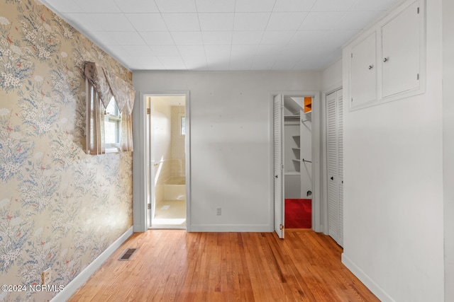 unfurnished bedroom featuring ensuite bathroom and light wood-type flooring