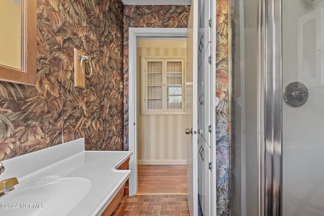 bathroom featuring hardwood / wood-style flooring, walk in shower, and sink