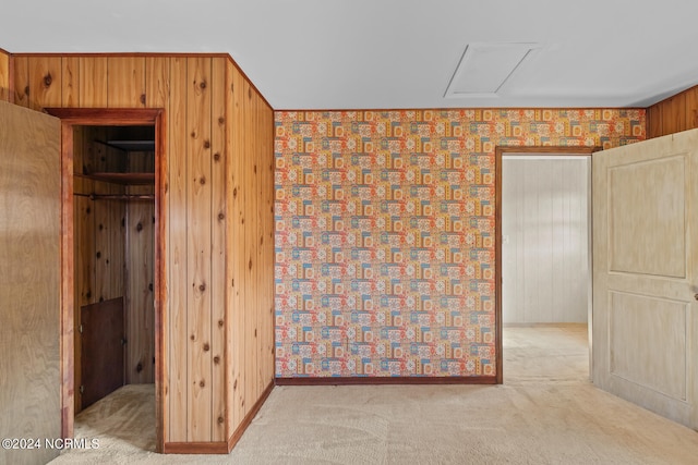 unfurnished bedroom featuring light carpet and wooden walls