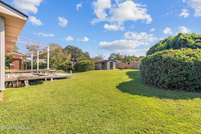 124 N Lisk Dr, Swansboro, NC 28584 - view of yard with a storage unit, a wooden deck, an outbuilding, and fence