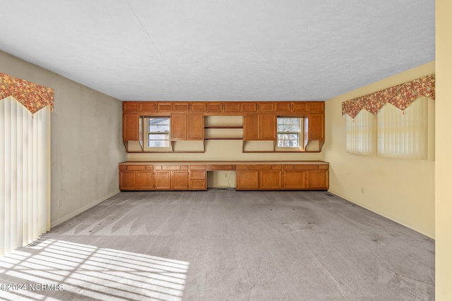 interior space with a textured ceiling, built in desk, and plenty of natural light