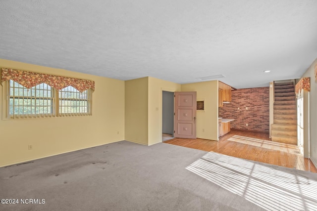 124 N Lisk Dr, Swansboro, NC 28584 - unfurnished living room with stairs, a textured ceiling, baseboards, and brick wall