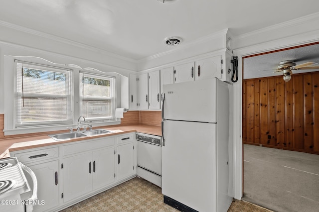 kitchen featuring white cabinetry, ornamental molding, sink, wooden walls, and white appliances