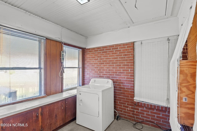 laundry area featuring brick wall, light carpet, and washer / clothes dryer