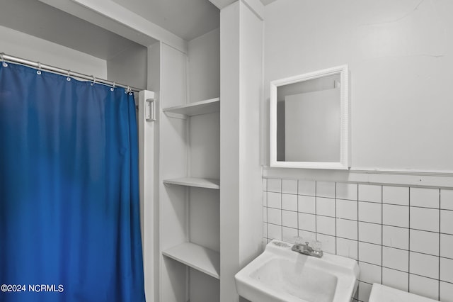 bathroom with tasteful backsplash, built in features, sink, and curtained shower