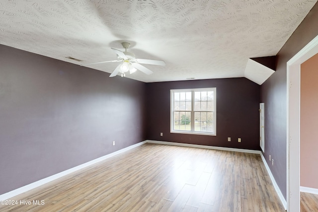 spare room with light wood-type flooring, lofted ceiling, a textured ceiling, and ceiling fan