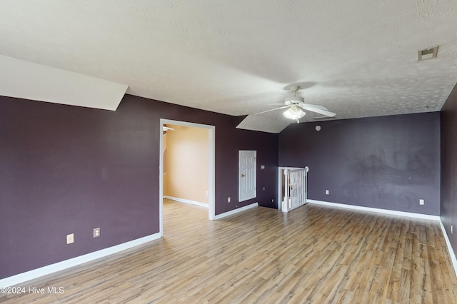 unfurnished living room with light hardwood / wood-style floors, a textured ceiling, ceiling fan, and vaulted ceiling