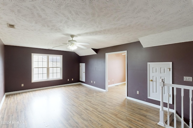 additional living space featuring ceiling fan, a textured ceiling, light wood-type flooring, and vaulted ceiling