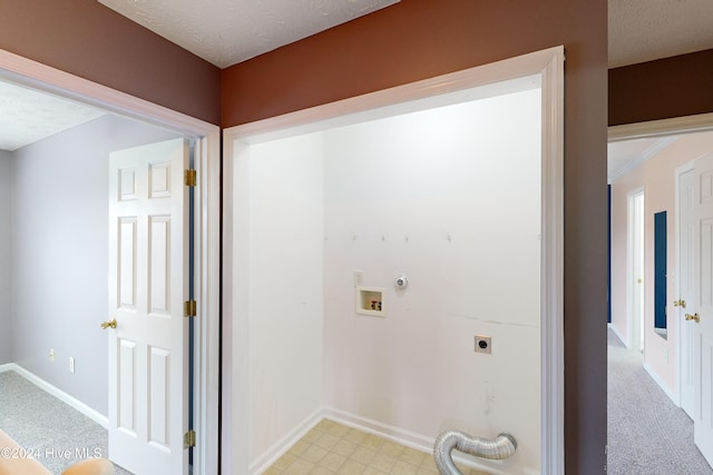 clothes washing area with electric dryer hookup, a textured ceiling, and light colored carpet