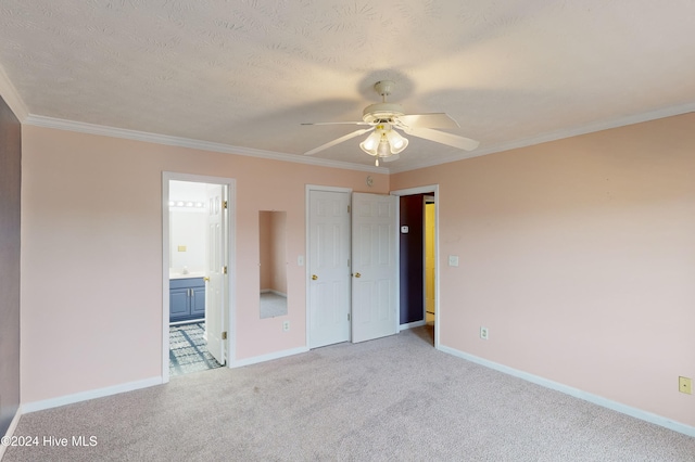 unfurnished bedroom featuring light colored carpet, ensuite bath, a textured ceiling, ceiling fan, and crown molding