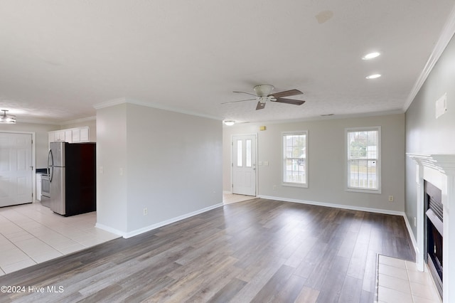 unfurnished living room with light hardwood / wood-style floors, ceiling fan, and ornamental molding