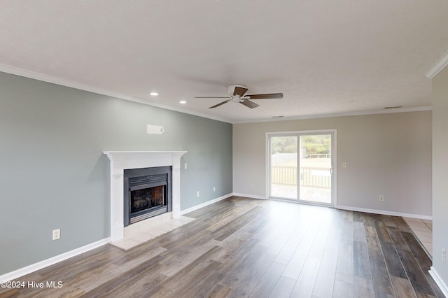 unfurnished living room with ornamental molding, a tiled fireplace, hardwood / wood-style floors, and ceiling fan