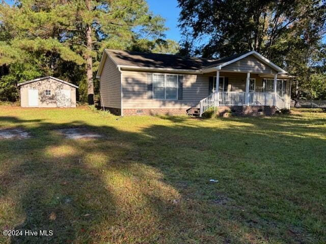 view of front of home with a porch, a front lawn, and a storage shed