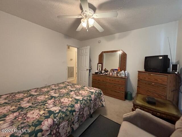 carpeted bedroom with a textured ceiling and ceiling fan