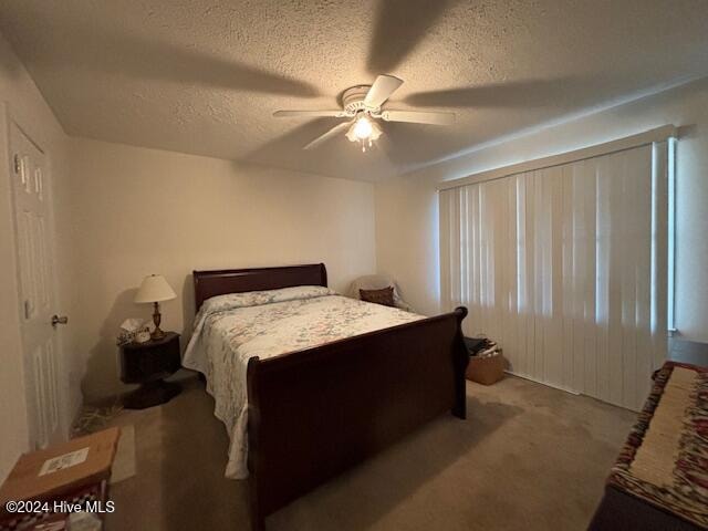 carpeted bedroom with ceiling fan and a textured ceiling