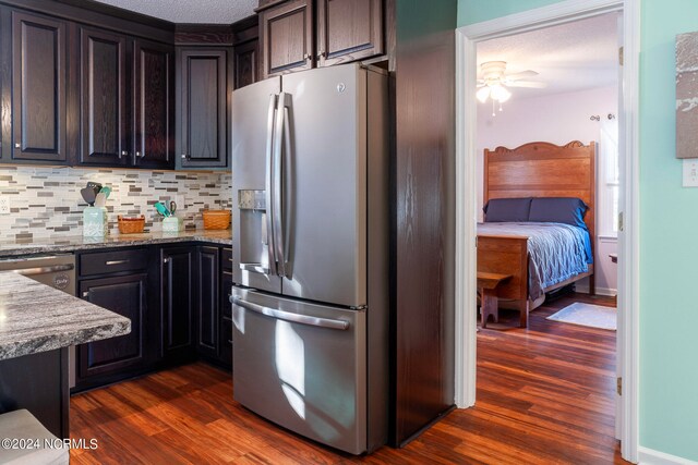 kitchen featuring tasteful backsplash, dark hardwood / wood-style flooring, ceiling fan, light stone counters, and stainless steel refrigerator with ice dispenser