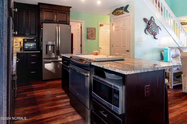 kitchen with dark brown cabinetry, a center island, appliances with stainless steel finishes, and dark wood-type flooring