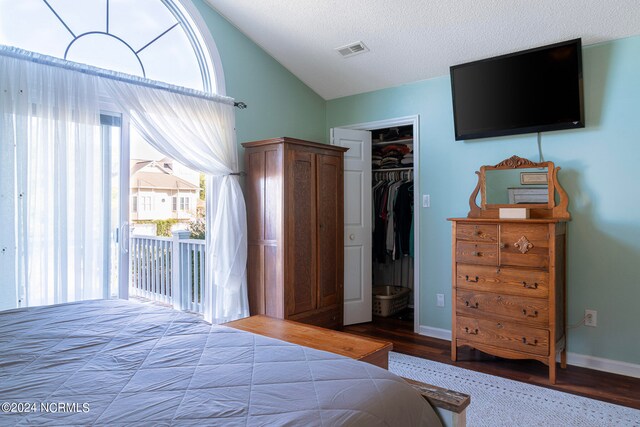 bedroom with a closet, hardwood / wood-style floors, a textured ceiling, and vaulted ceiling