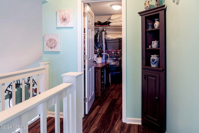 hall with a textured ceiling and dark hardwood / wood-style flooring