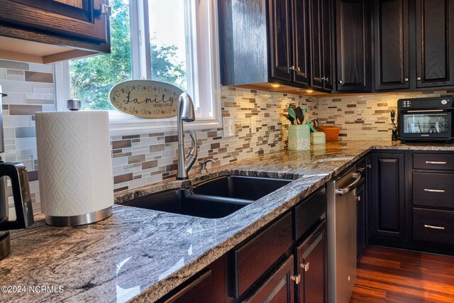 kitchen with light stone countertops, sink, dark wood-type flooring, and backsplash