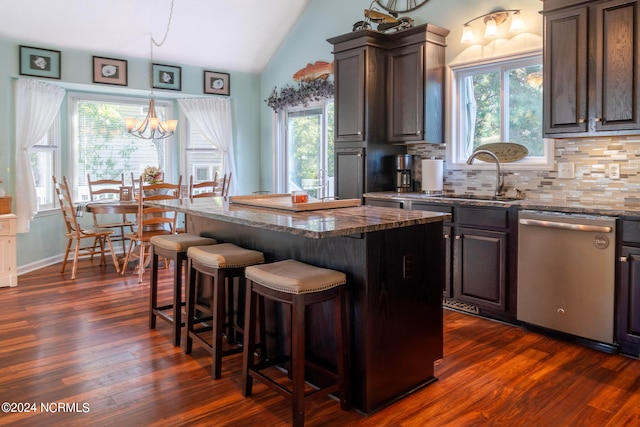 kitchen with dark hardwood / wood-style flooring, a kitchen breakfast bar, a kitchen island, stainless steel dishwasher, and sink