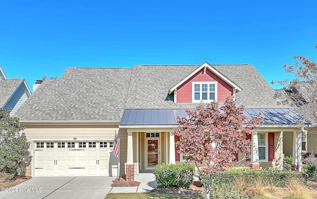 view of front of property with a shingled roof, metal roof, driveway, an attached garage, and a standing seam roof