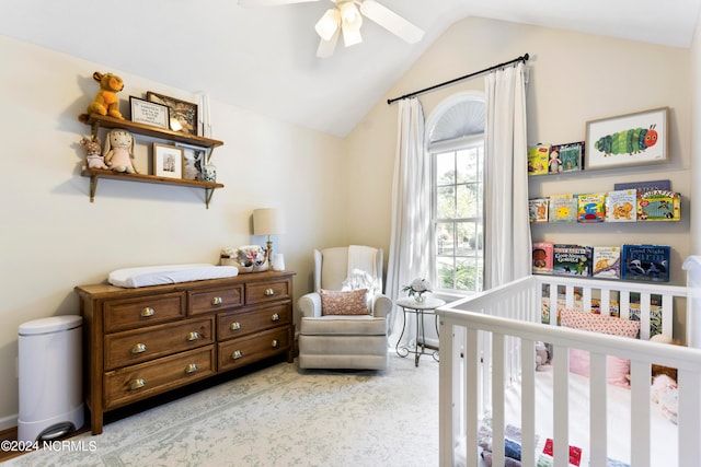 bedroom with ceiling fan, lofted ceiling, light colored carpet, and a crib