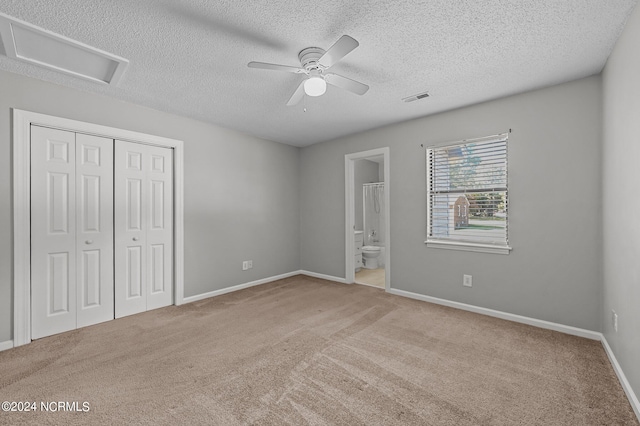 unfurnished bedroom featuring ensuite bath, light carpet, a closet, and ceiling fan