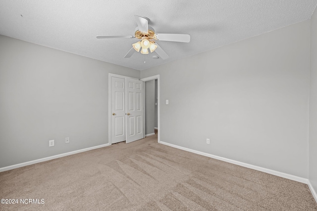 carpeted spare room featuring a textured ceiling and ceiling fan