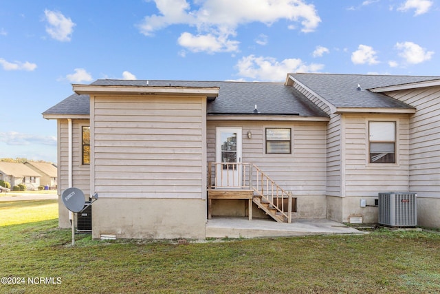 rear view of property featuring central AC and a lawn