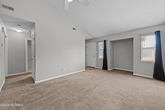 unfurnished bedroom with lofted ceiling, a textured ceiling, light colored carpet, and ceiling fan