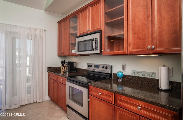 kitchen with dark stone countertops, appliances with stainless steel finishes, and light tile patterned floors