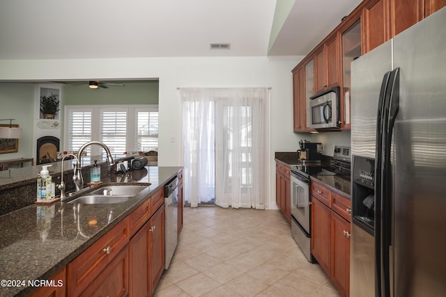 kitchen with stainless steel appliances, a sink, a ceiling fan, glass insert cabinets, and light tile patterned floors