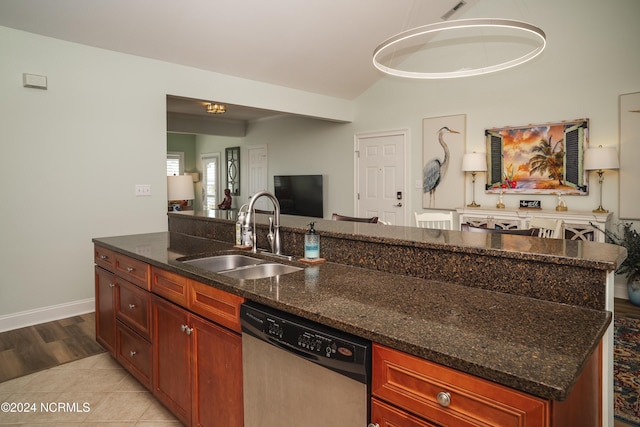 kitchen with a sink, stainless steel dishwasher, open floor plan, light tile patterned floors, and dark stone counters