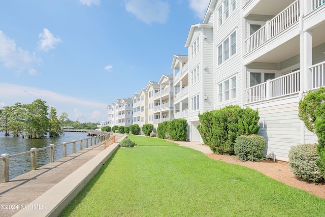 surrounding community with a water view and a lawn
