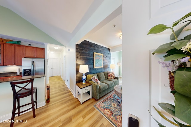 living room with lofted ceiling, light hardwood / wood-style flooring, and wood walls