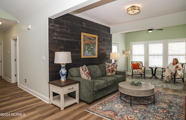 living area featuring crown molding, wood finished floors, baseboards, and a ceiling fan