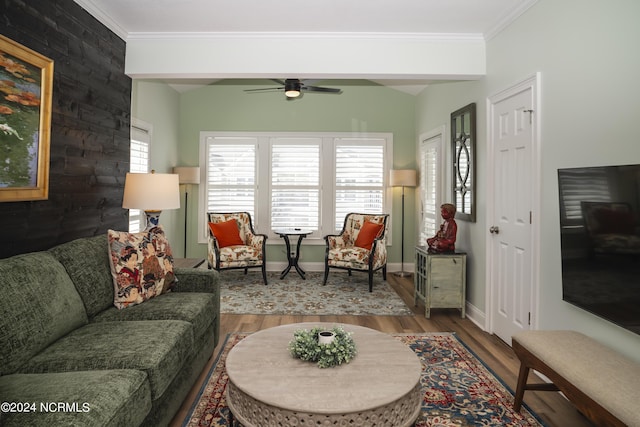 living area featuring wood finished floors, crown molding, a ceiling fan, and baseboards