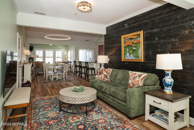 living room with crown molding, hardwood / wood-style flooring, and wood walls