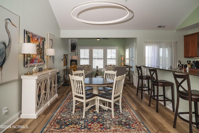 dining room with vaulted ceiling, wood finished floors, and baseboards