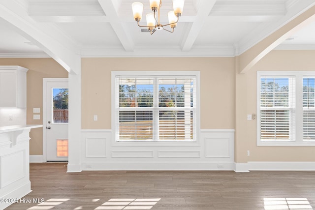 unfurnished dining area with arched walkways, a chandelier, wainscoting, and light wood-type flooring