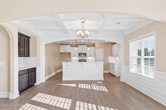 46 Covey Ct, Hampstead, NC 28443 - kitchen with light wood-style floors, arched walkways, stainless steel microwave, and a chandelier