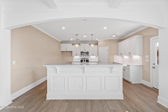 kitchen featuring a spacious island, white cabinets, decorative light fixtures, and light wood-type flooring